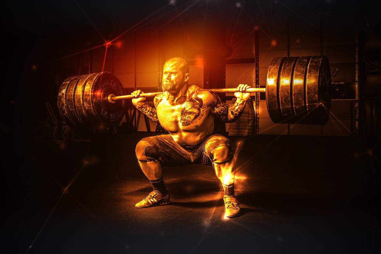 A man lifting a barbell in a gym. He is in a squat position with his feet shoulder-width apart and his arms extended above hi...