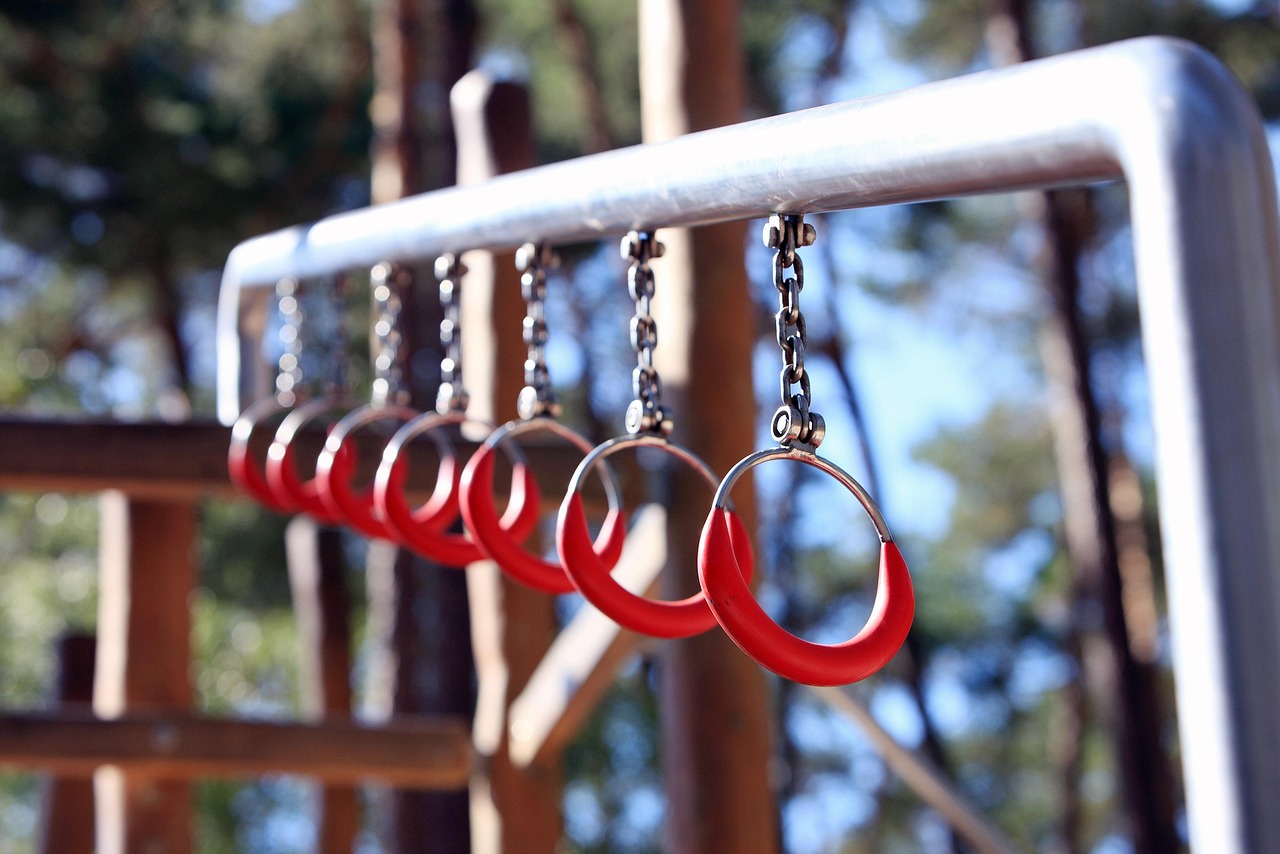 A row of red rings hanging from a metal chain attached to a metal railing. The rings are circular in shape and appear to be m...