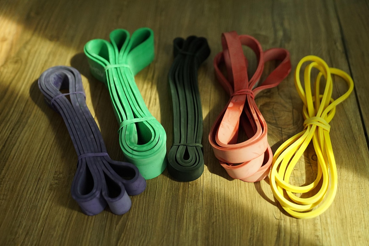 Four different types of resistance bands laid out on a wooden surface. The bands are of different colors - purple, green, bla...