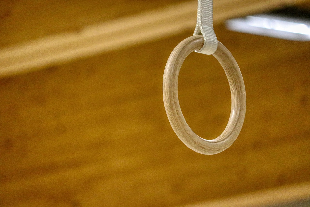A wooden ring hanging from a white string. The ring appears to be made of a light-colored wood and has a smooth, polished fin...