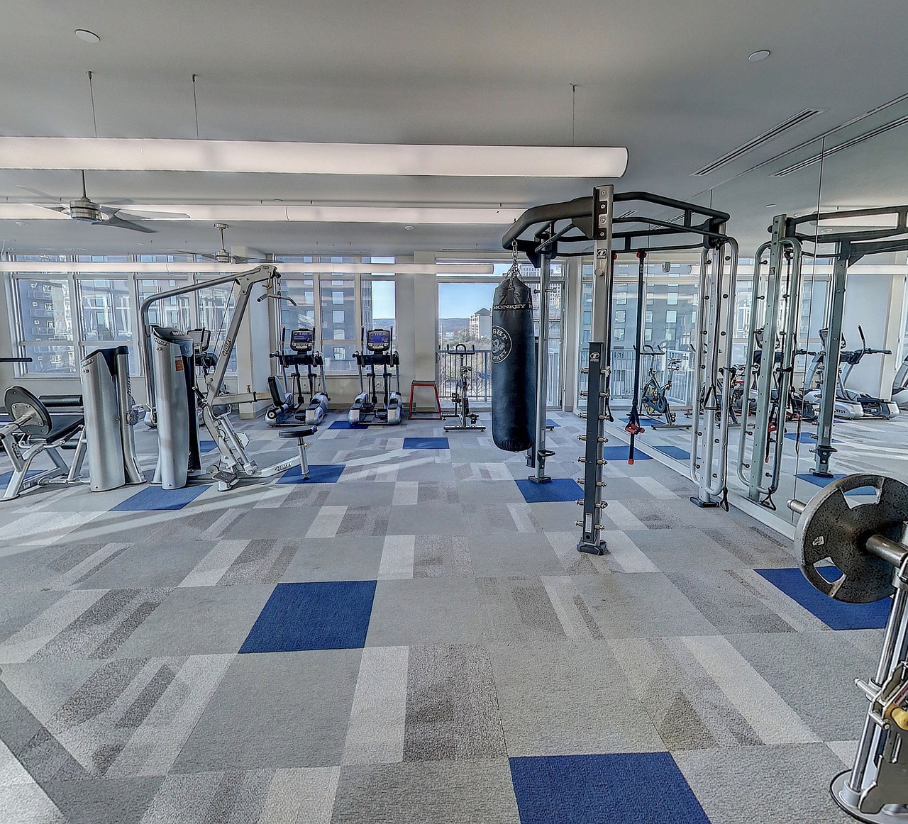 A modern and well-equipped gym with various exercise equipment. The floor is covered with blue and white checkered tiles, and...
