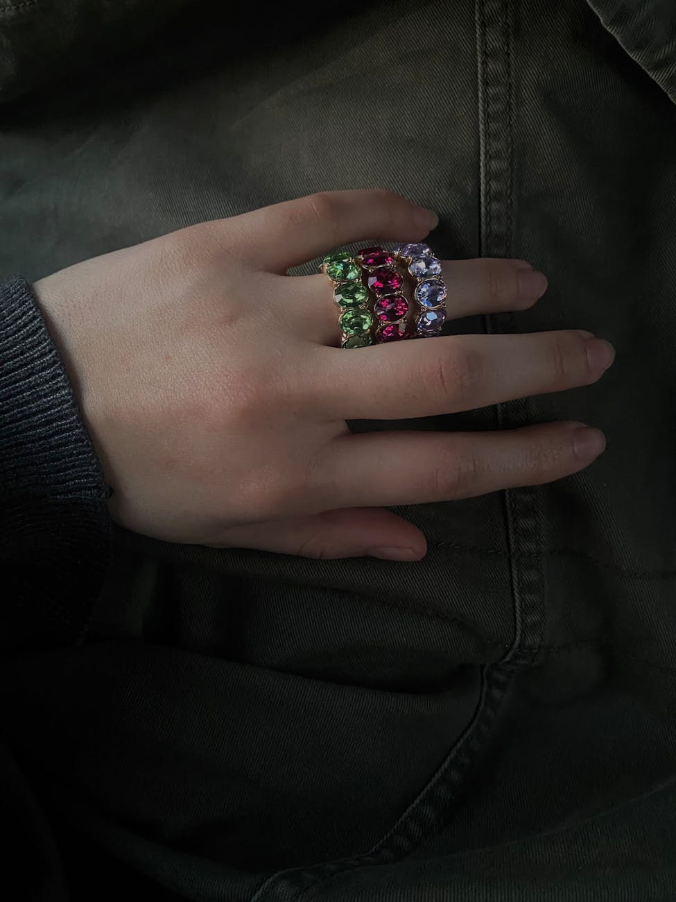 A close-up of a person's hand resting on a black jacket. The hand is resting on the pocket of the jacket, and the person is w...