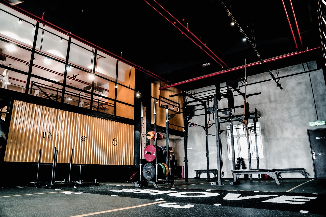 The interior of a gym with various exercise equipment. The floor is covered with a black and white patterned rug with the wor...